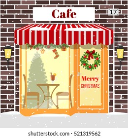 Christmas decorated cafe or coffee shop. Illuminated facade of red bricks with window, table, chair, mulled wine drink, wreath, garland, xmas tree, snowflakes. Vector. For postcards, prints, banner