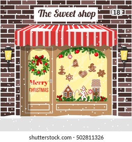 Christmas Decorated And Illuminated Sweet Shop, Candy Store, Confectionery. Cozy Brick Building Facade With Entrance, Awning, Door, Shopfront, Gingerbread Man, Wreath, Garland, Lollipop, Lamps. Vector