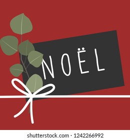 Christmas design with an eucaliptus branch, black paper card with message "Noël" and white ribbon on red background.