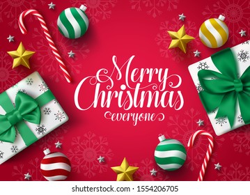 Christmas greeting vector banner design. Merry christmas typography greeting text for holiday season with decoration of xmas gift, ball, star and candy cane in red background with snowflakes pattern. 