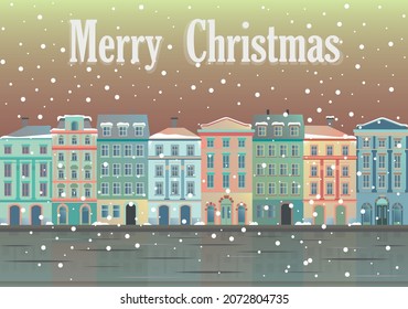 Christmas greetings from at snowy city. House facades in warm soft colors that are reflected in frozen water.