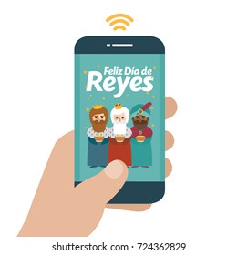 Christmas is here. Send your letter to The three wise men of orient from your cell phone. Hand holding smartphone. Happy day of kings written in spanish