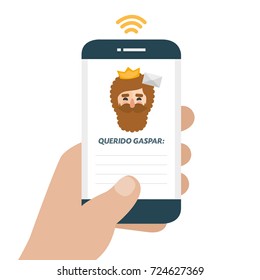 Christmas is here. Send your letter to The three wise men of orient from your cell phone. Hand holding smartphone. Dear Caspar written in spanish