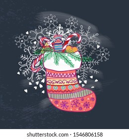 Christmas multicolored sock with gift,candy and other decorations on blackboard 