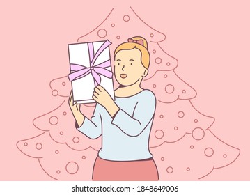 Christmas or New year concept. Young cheerful blonde girl holding gift box and rejoices. Christmas holiday celebration, winter season tradition.