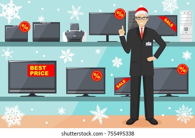 Christmas And New Year Sale. Manager, Seller In The Santa Claus Hat In Store On The Background Of Shelves With Appliances: TV, Computer, Laptop, Printer, Monitor. The Salesman In The Electrical Shop.