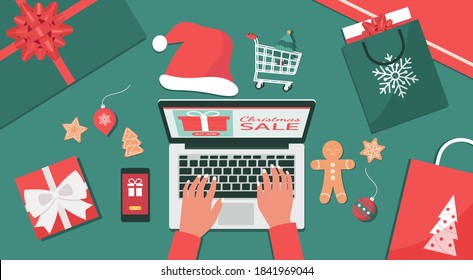 Christmas online shopping or winter holiday sale top view concept, human hand makes order on laptop screen with gift boxes and shopping bags, flat lay vector illustration