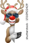 Christmas reindeer red nosed deer cartoon character wearing cool shades or sunglasses and a Santa hat peeking around a sign and pointing at it