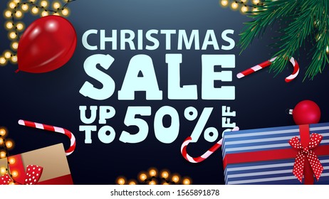 Christmas sale, up to 50% off, blue greeting card with presents, red balloon, candy cans, garland and Christmas tree branches, top view
