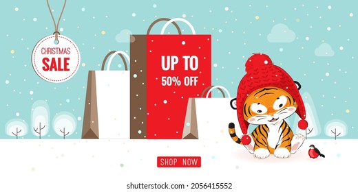 Christmas sale banner with cute little cartoon tiger cub wearing red knitted hat sits at big gift bags, holiday snowy winter landscape. 2022 New Year chinese calendar mascot. Vector Xmas illustration