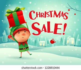 Christmas Sale! Little elf holds up gift present in Christmas snow scene winter landscape.