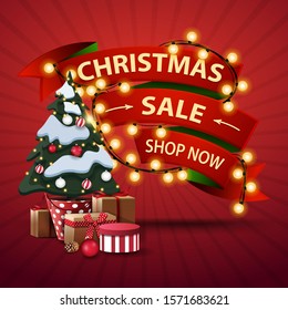 Christmas sale, shop now, discount banner in the form of ribbons wrapped garland and Christmas tree in a pot with gifts