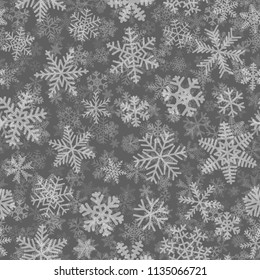 Christmas seamless pattern of many layers of snowflakes of different shapes, sizes and transparency. White on gray background