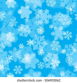 Christmas seamless pattern with white blurred and clear snowflakes on light blue background.