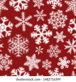 Christmas seamless pattern of white defocused snowflakes on red background
