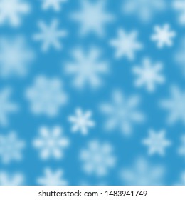 Christmas seamless pattern of white defocused snowflakes on light blue background