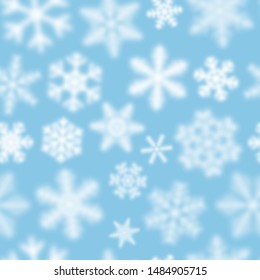 Christmas seamless pattern of white defocused snowflakes on light blue background