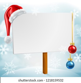 A Christmas sign with a Santa Claus hat and bauble decorations in a winter snow scene with snowflakes falling