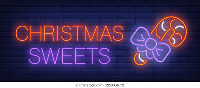 Christmas sweets neon sign. Glowing inscription with red candy cane and purple ribbon on brick wall background. Vector illustration can be used for Christmas, confectionary, sweet shop