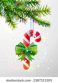 Christmas tree branch with candy cane decorated ribbon. Striped candy stick with bow hanging on pine twig