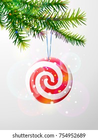 Christmas tree branch with round candy. Striped peppermint lollipop hanging on pine twig