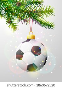 Christmas tree branch with soccer ball. Christmas bauble of football ball hanging on pine twig