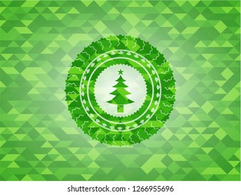 christmas tree icon inside green emblem with triangle mosaic background