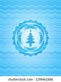 christmas tree icon inside sky blue water wave style badge.