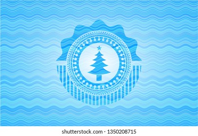 christmas tree icon inside sky blue water wave style emblem.