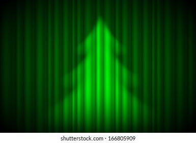 Christmas tree in spotlight on green curtain. Theatre style.