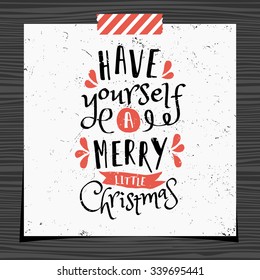 Christmas typographic design greeting card template. Have Yourself a Merry Little Christmas message in black and red on white background. Christmas card with a strip of washi tape on wood background.