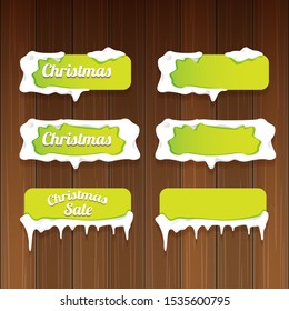 Christmas vector green glossy buttons set isolated on wooden background. web green christmas sale buttons with snow, ice border