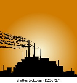 Circuit of industrial buildings and smoking chimneys against the setting sun.