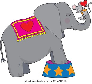 A circus elephant standing on a circus tub, has a mouse with a red heart on her trunk.