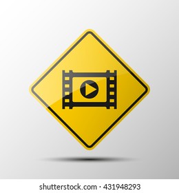Clapperboard Icon, yellow diamond road sign with a black border and an image reel of film on white background. Vector Illustration