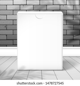 Closed white cardboard box is near the brick wall on the plank floor. Front view.  The shadow of the palm tree is on top. Mockup for design