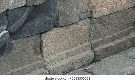 a close-up of an ancient stone wall, likely part of a temple structure. The texture appears weathered and rough, with visible cracks and variations in stone color.