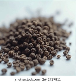 A close-up shot reveals a pile of dark brown peppercorns scattered on a light-colored surface, their rough textures and individual shapes highlighted against the blurry background.