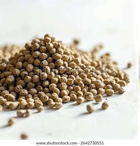 A close-up shot reveals a substantial pile of light brown, round seeds or grains, possibly chickpeas or similar legumes, resting on a lightly textured off-white surface.