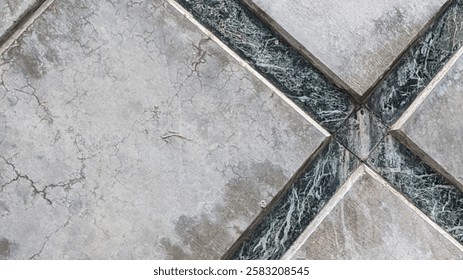 A close-up of weathered, cracked tiles with a geometric pattern, featuring aged stone or ceramic surfaces separated by dark marble-like strips. The texture is rough, worn, and detailed.