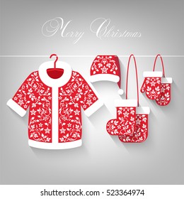 Clothes hangs on a rope on light grey background. Merry Christmas text. Red coats, hats, mittens, shoes with beautiful ornament. White applique on red material.
