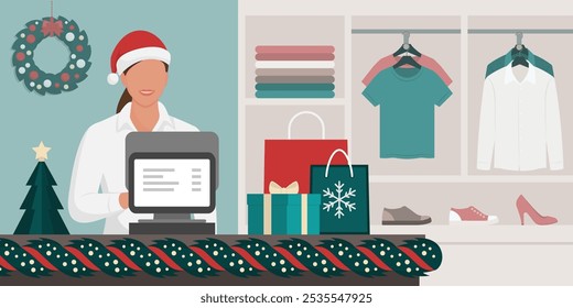 Clothing shop interior with Christmas decorations and happy saleswoman wearing a Santa hat, holidays and celebrations concept