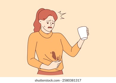 Clumsy woman spills coffee on sweater and needs urgent washing to prevent stain from drying. Clumsy girl makes unhappy grimace due to pain caused by spilled hot drink from white mug