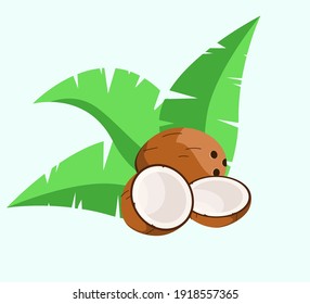 Coconut split and whole against the background of green palm leaves