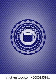 coffee cup icon inside badge with denim texture. 