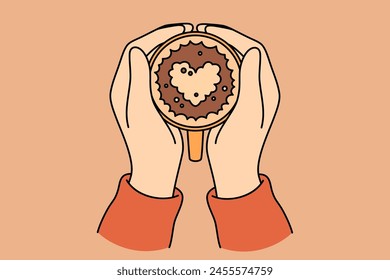 Coffee with foam heart in hands of person drinking hot drink from cup and enjoying aroma. Fresh cocoa or latte coffee for cozy autumn evening, and opportunity to relax after returning from street
