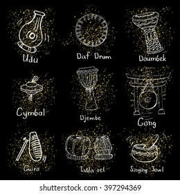 Collection of ethnic percussion instruments on golden dusty stains on black background.