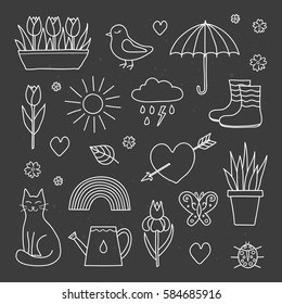 Collection of hand drawn outline spring items including sun, cloud, umbrella, boots, flowers, cat, bird, butterfly, ladybug and rainbow isolated on the blackboard.