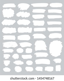 Collection of miscellaneous grunge brush strokes in white isolated over light grey background. Set of design elements. Vector illustration.