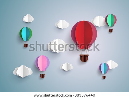 A collection of rainbow paper balloons flying in blue sky with soft white clouds.